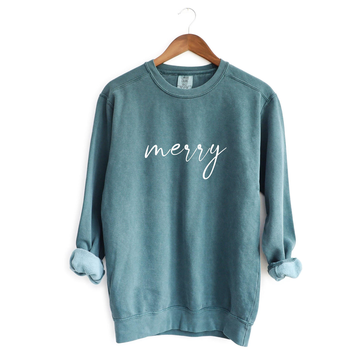 Green crewneck sweatshirt with merry in white cursive on a hanger